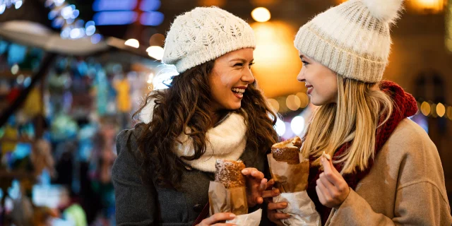 Happy people having fun together at a festive christmas fair. Christmas holiday happiness people concept