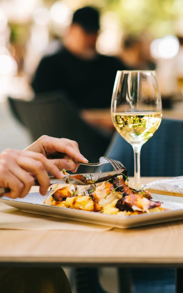 a glass of beer and wine on a table with dishes two girls have lunch together in a restaurant on the terrace